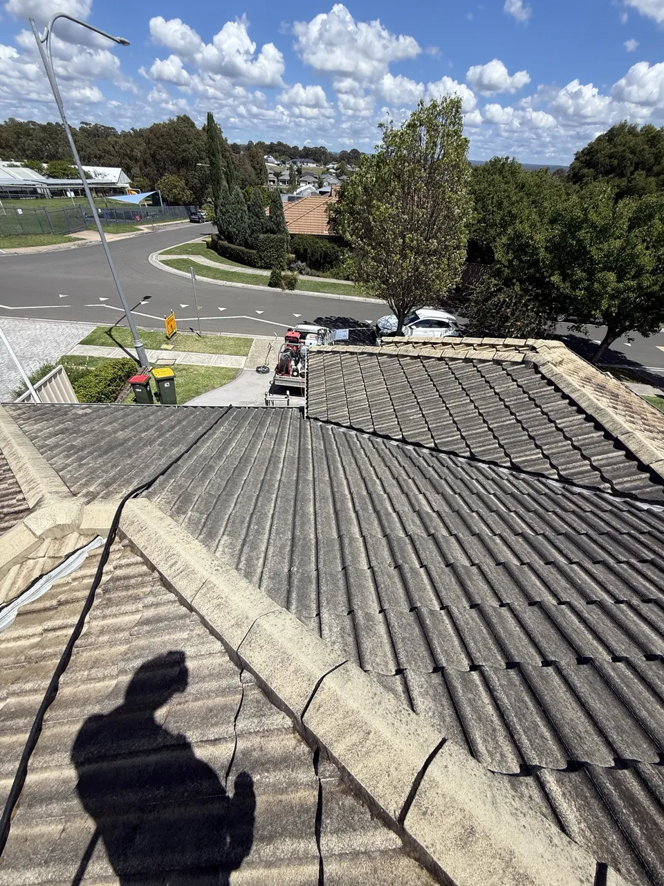 Tile roof part way through a soft wash, with a clean strip next to dark tiles