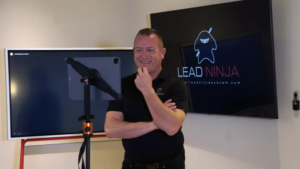 Gene Slade stands beside a whiteboard in a Lead Ninja training room, arms crossed, smiling