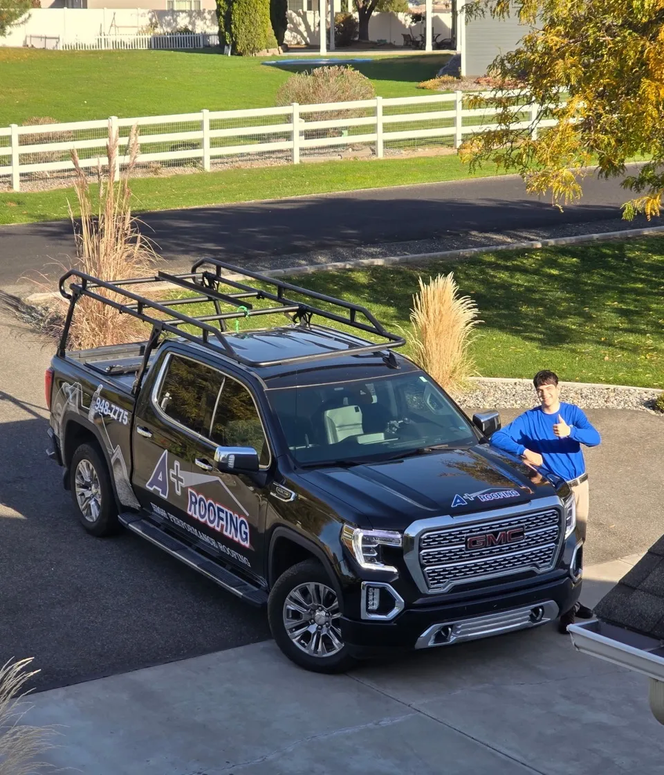 A+ Roofing crew member beside a branded GMC roofing truck
