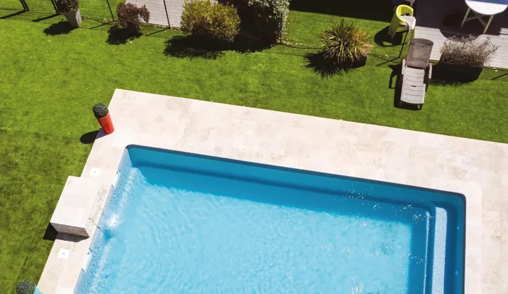 Piscine vue du dessus avec jardin et terrasse claire