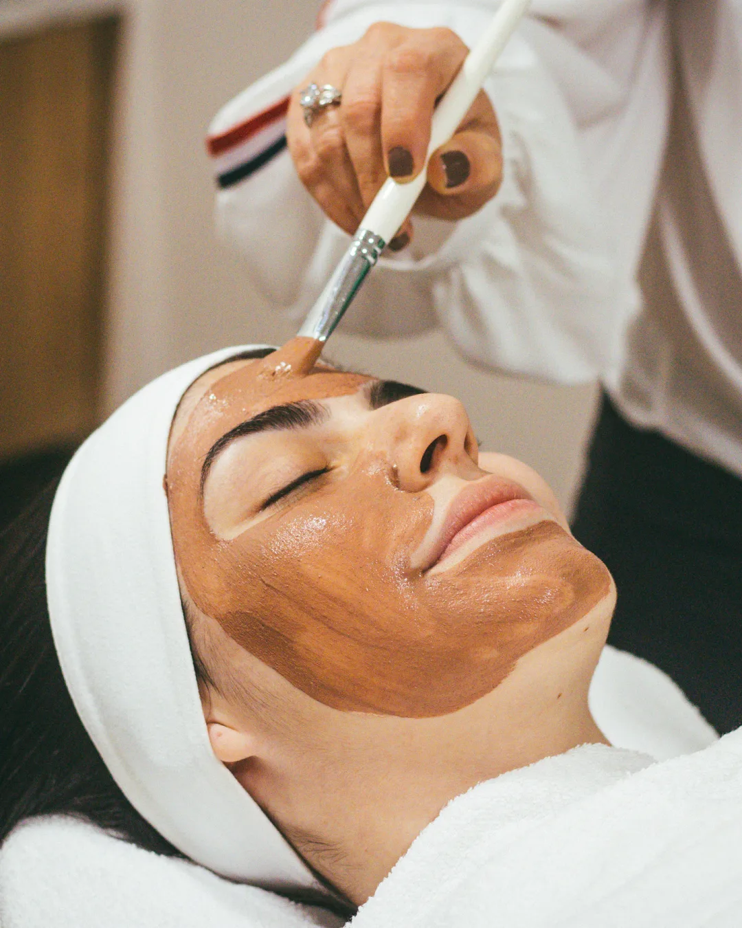 Esteticista aplicando una mascarilla facial a una clienta