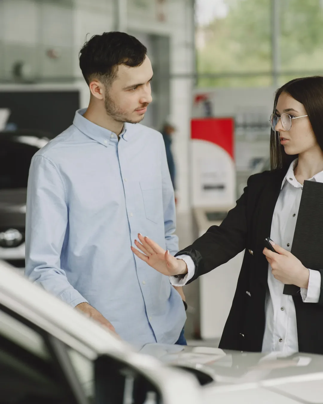 Vendedora mostrándole un auto a un cliente en el concesionario