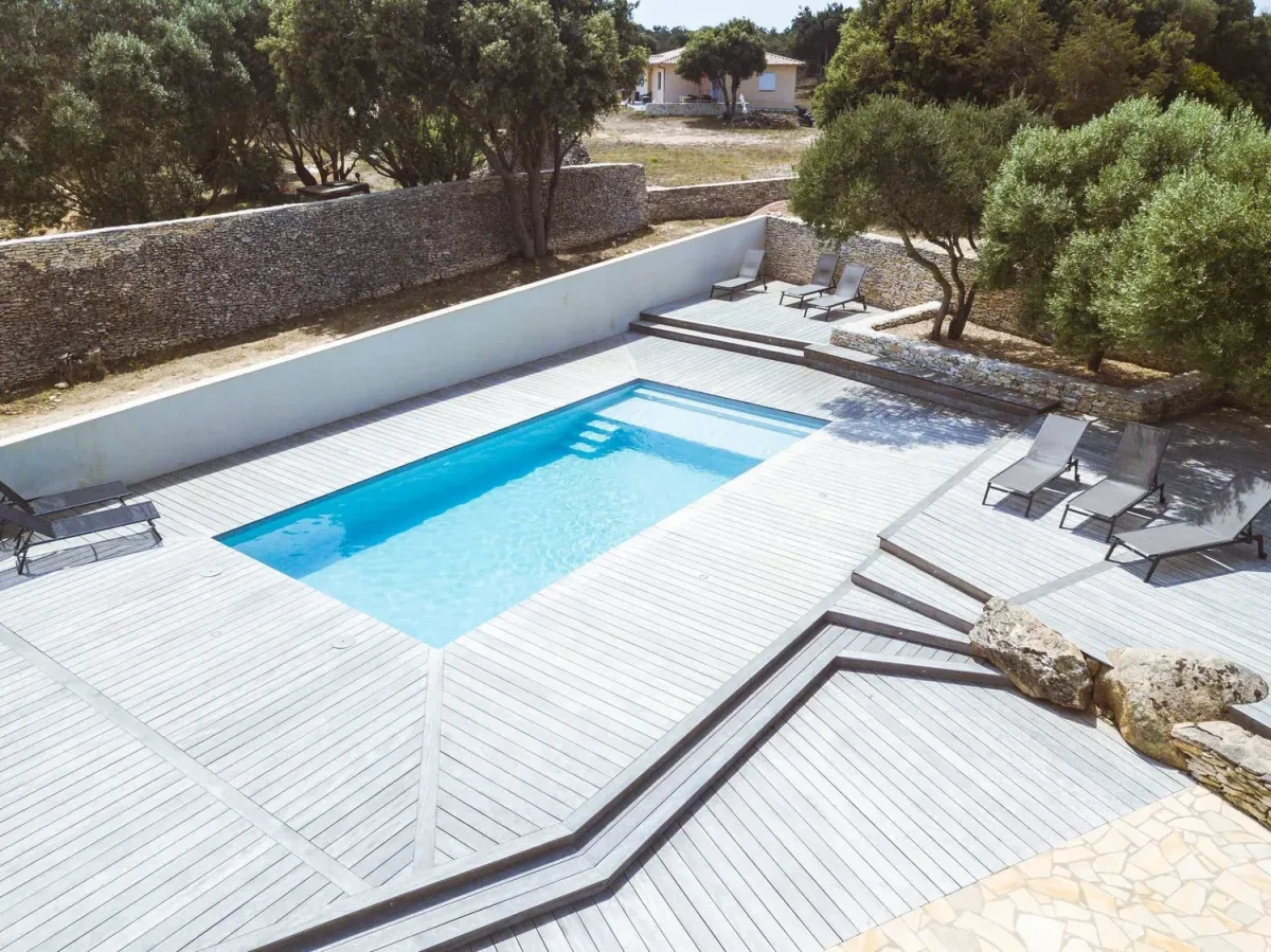 Piscine coque avec plage et environnement en pierre