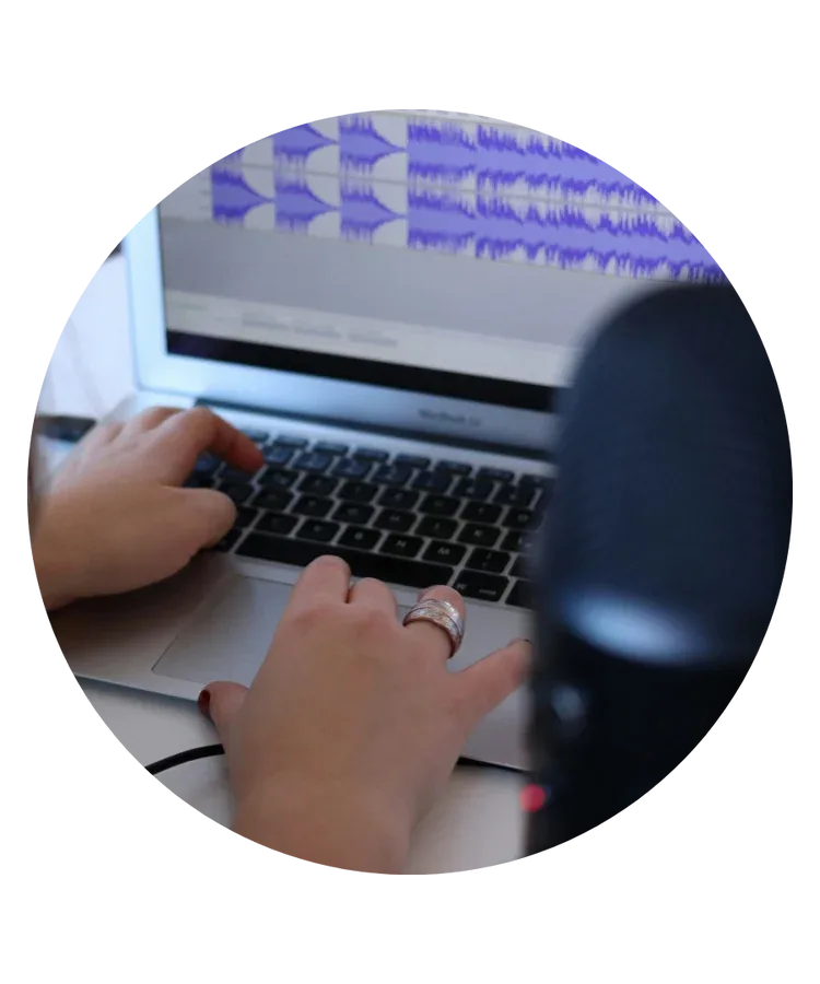 Person editing content on a laptop with a microphone nearby