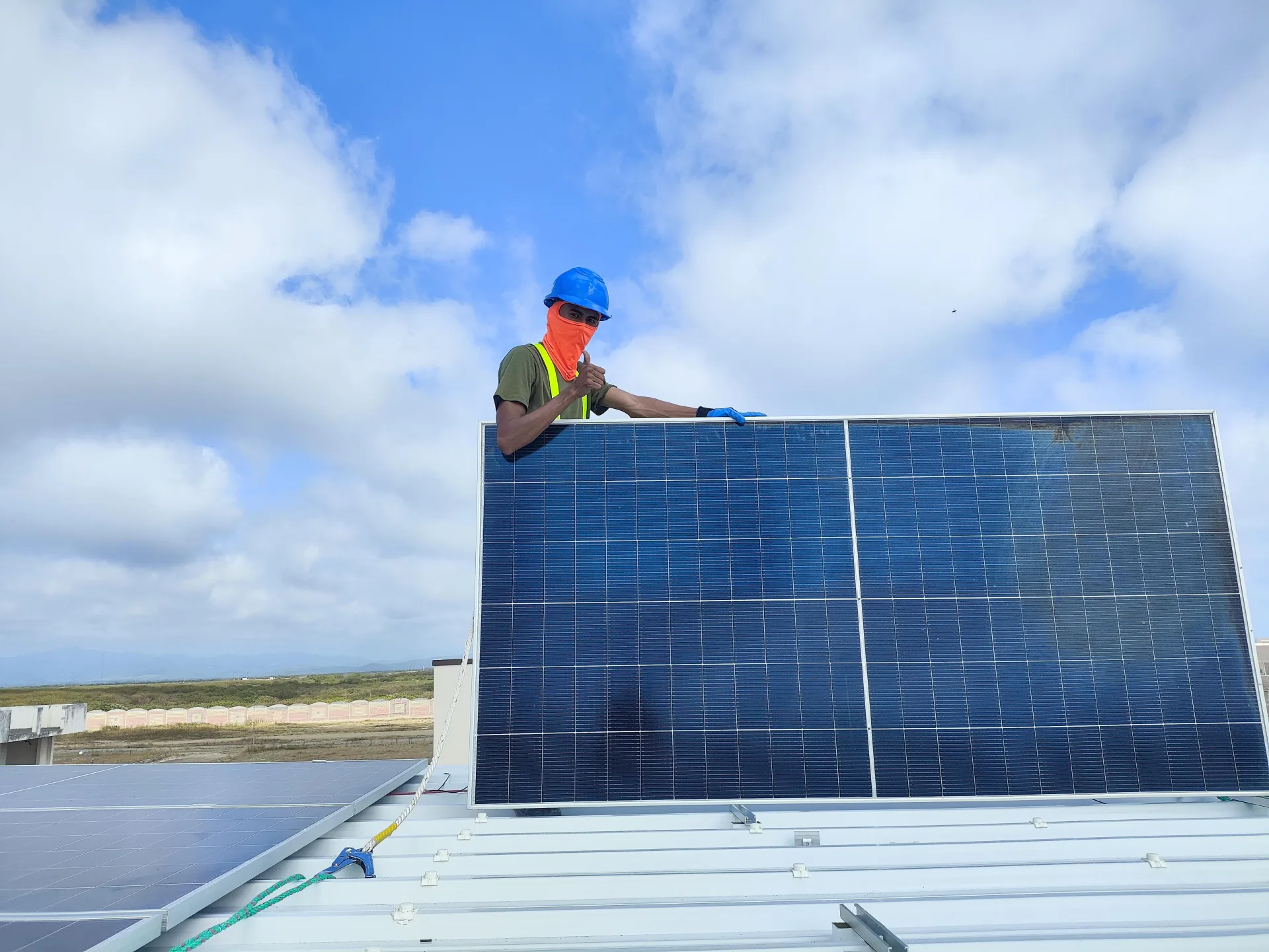 Técnico de NACARK instalando un panel solar contra el cielo despejado en Ecuador