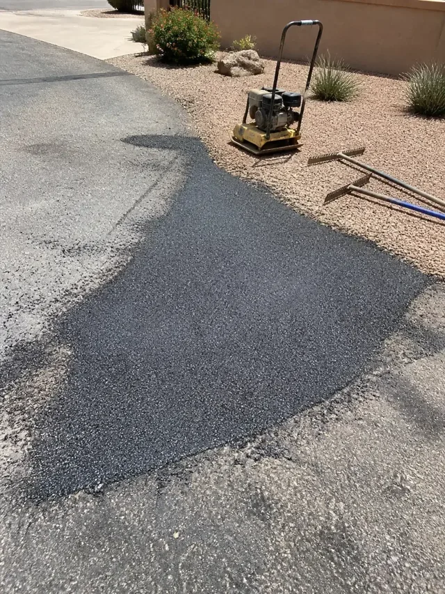 Newly patched asphalt driveway repair with construction tools in Scottsdale, AZ.