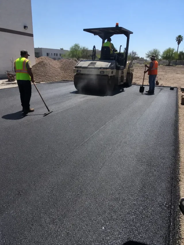 Construction crew paving a commercial lot with a steamroller in Scottsdale, AZ.