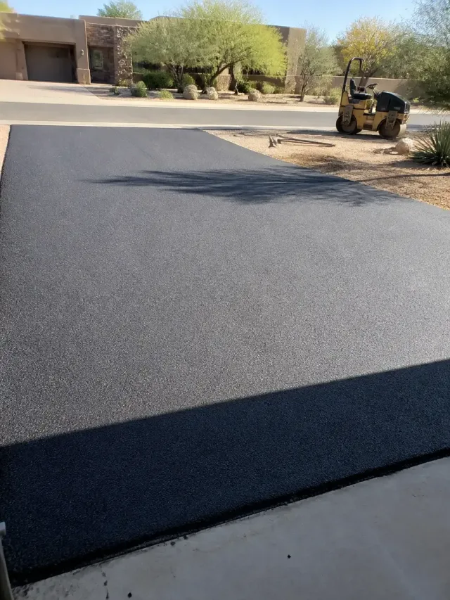Newly paved black asphalt driveway next to desert landscaping in Scottsdale, AZ.
