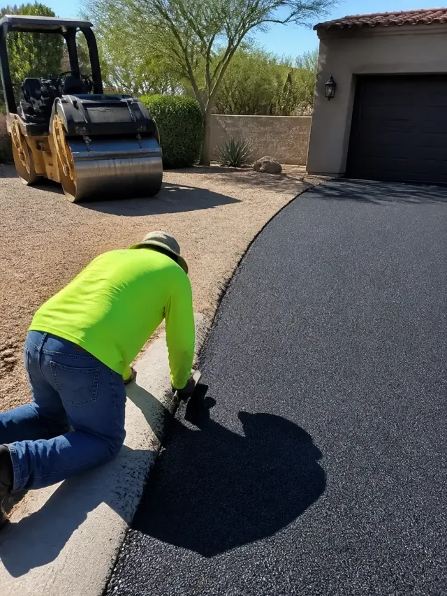 Construction worker using a hand tool to finish a new asphalt driveway in Scottsdale, AZ.