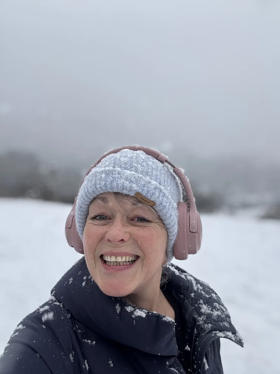Emma laughing in the snow, wearing a beanie and headphones