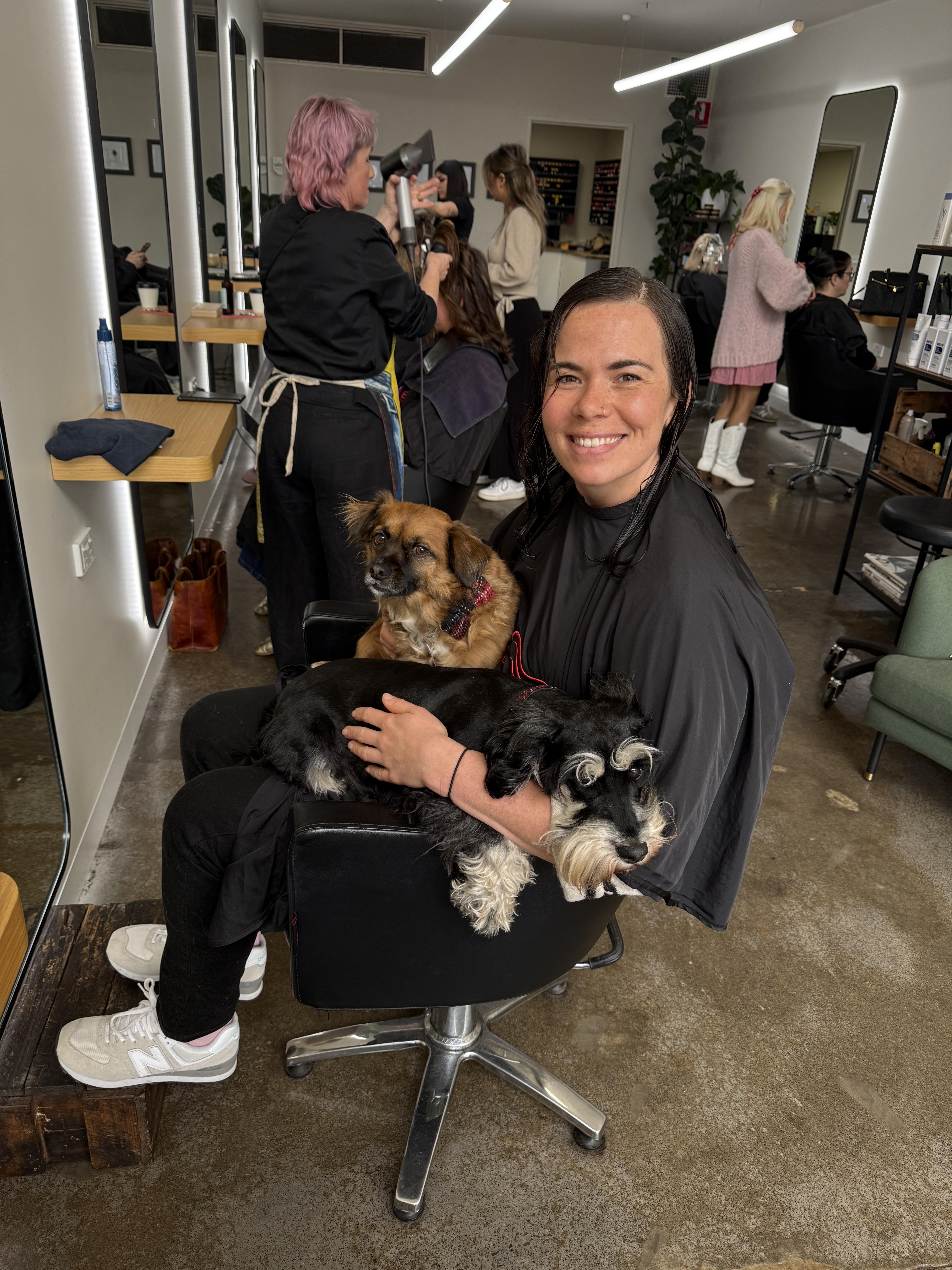 A BIBA Croydon stylist smiling, holding the salon dog