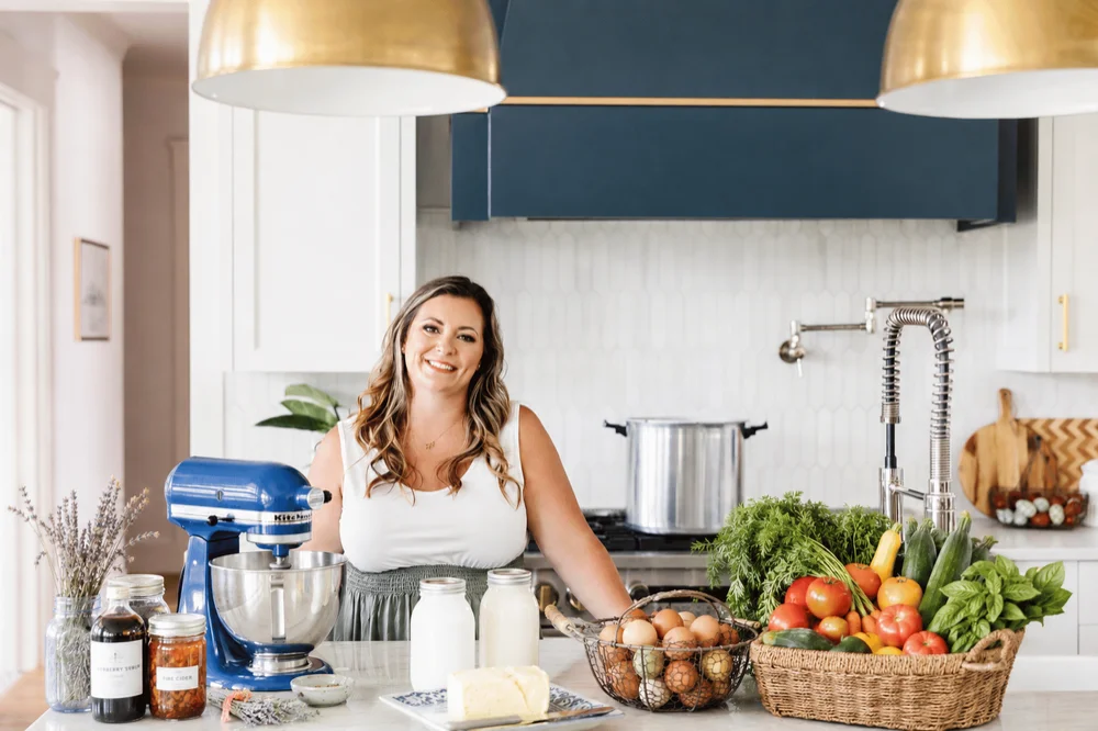 Shelby DeVore in her kitchen with fresh vegetables, eggs, and homemade staples