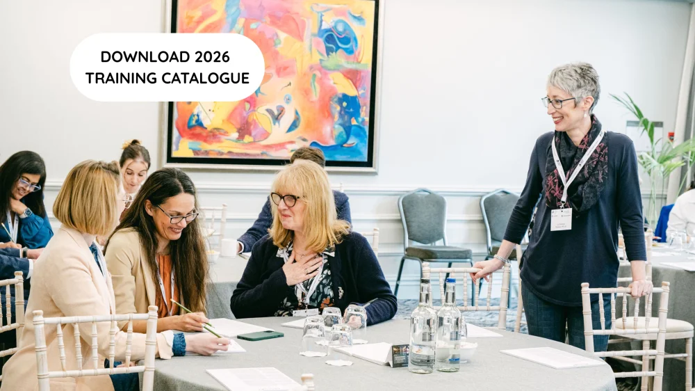 Liz standing by a table of attendees who are all smiling