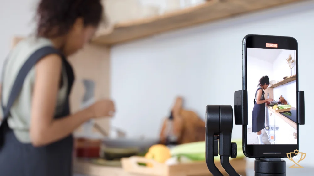 Through mobile phone camera view of kitchen blogger or vlogger at work