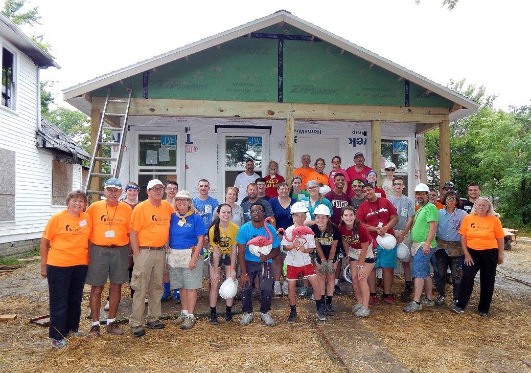Group of volunteers in front of a house project, smiling and celebrating the work of the Fuller Center for Housing of Delaware.