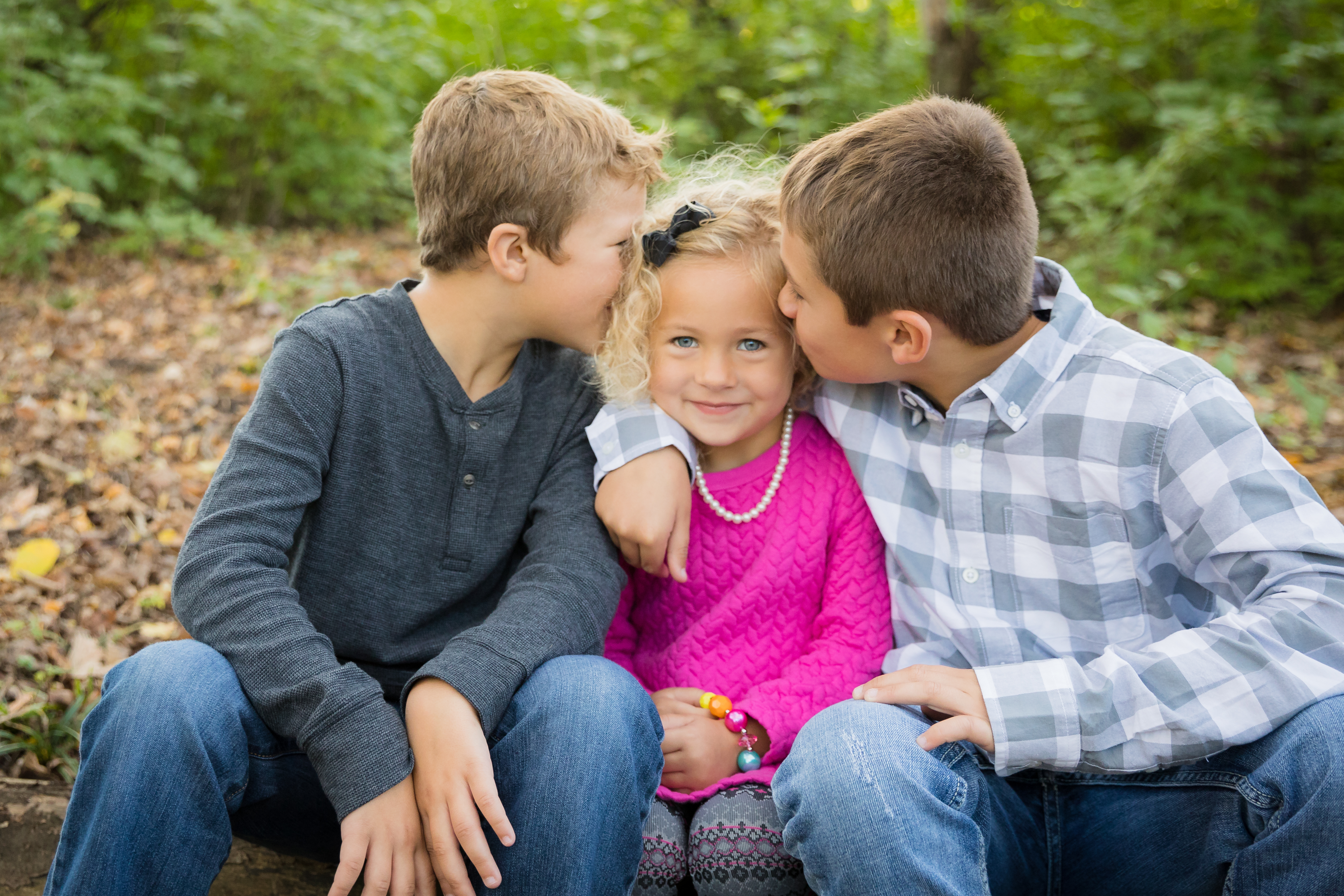 Three siblings in a fall park setting in coordinating outfits for the family photo session.