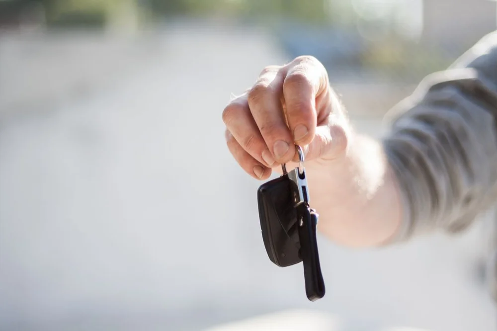 Eine Hand übergibt einen Fahrzeugschlüssel