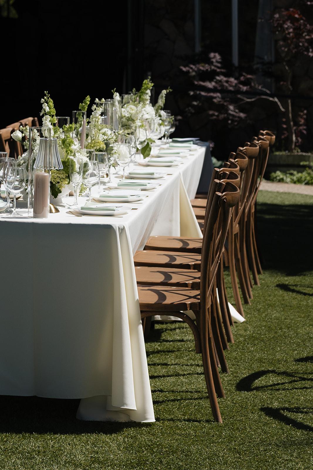 Linen-covered table set with glassware and flowers on the lawn