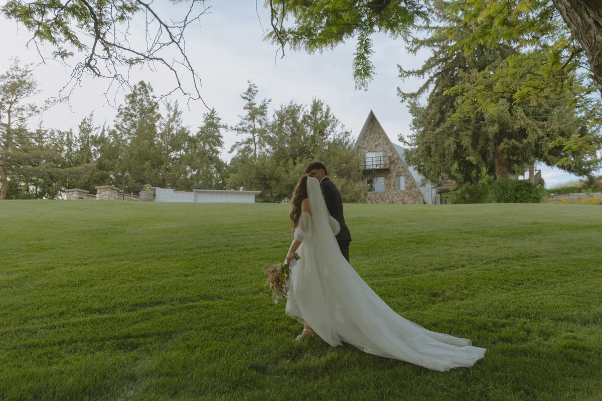 Newly married couple on the lawn with the stone estate behind them