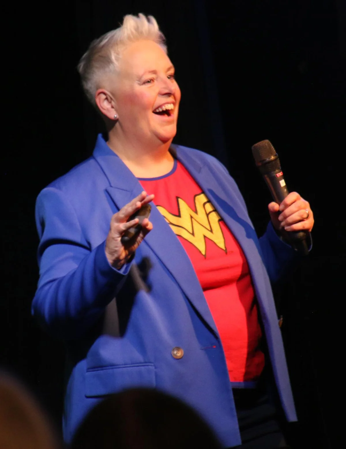 Suzi Payton on stage with a microphone, laughing