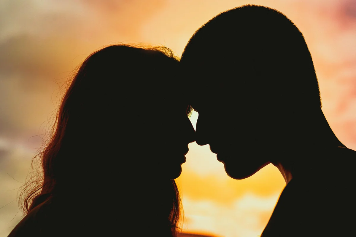 Silhouette of a couple touching foreheads at sunset