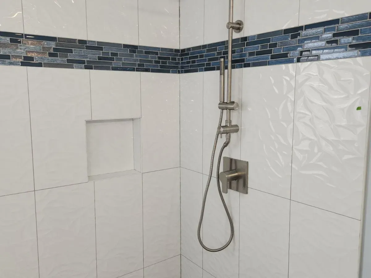White subway tile shower with blue glass mosaic accent band