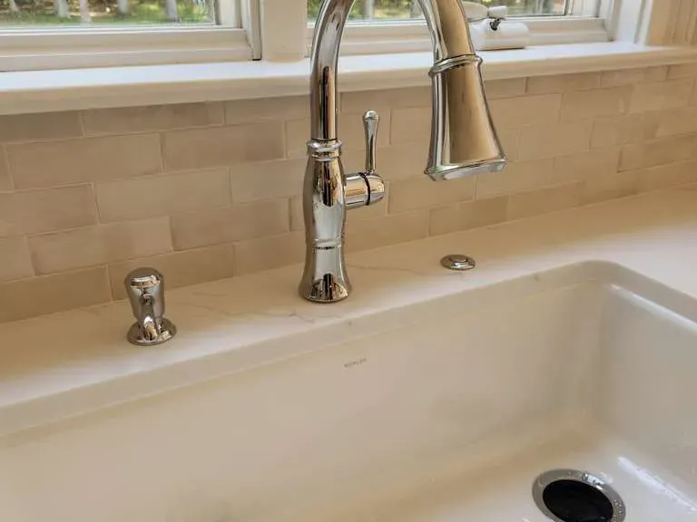 Apron-front kitchen sink with chrome faucet and subway-tile backsplash