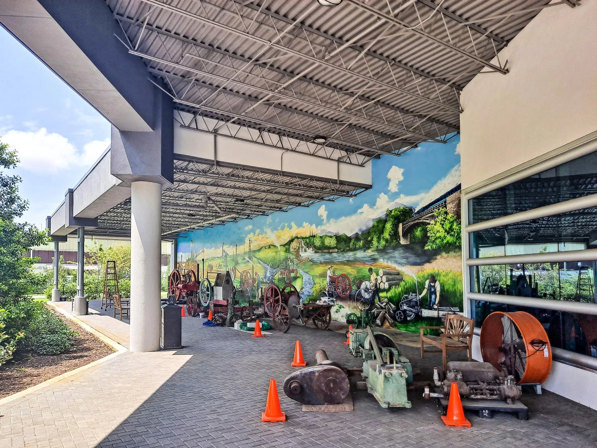 Panoramic hand-painted landscape mural along a covered walkway