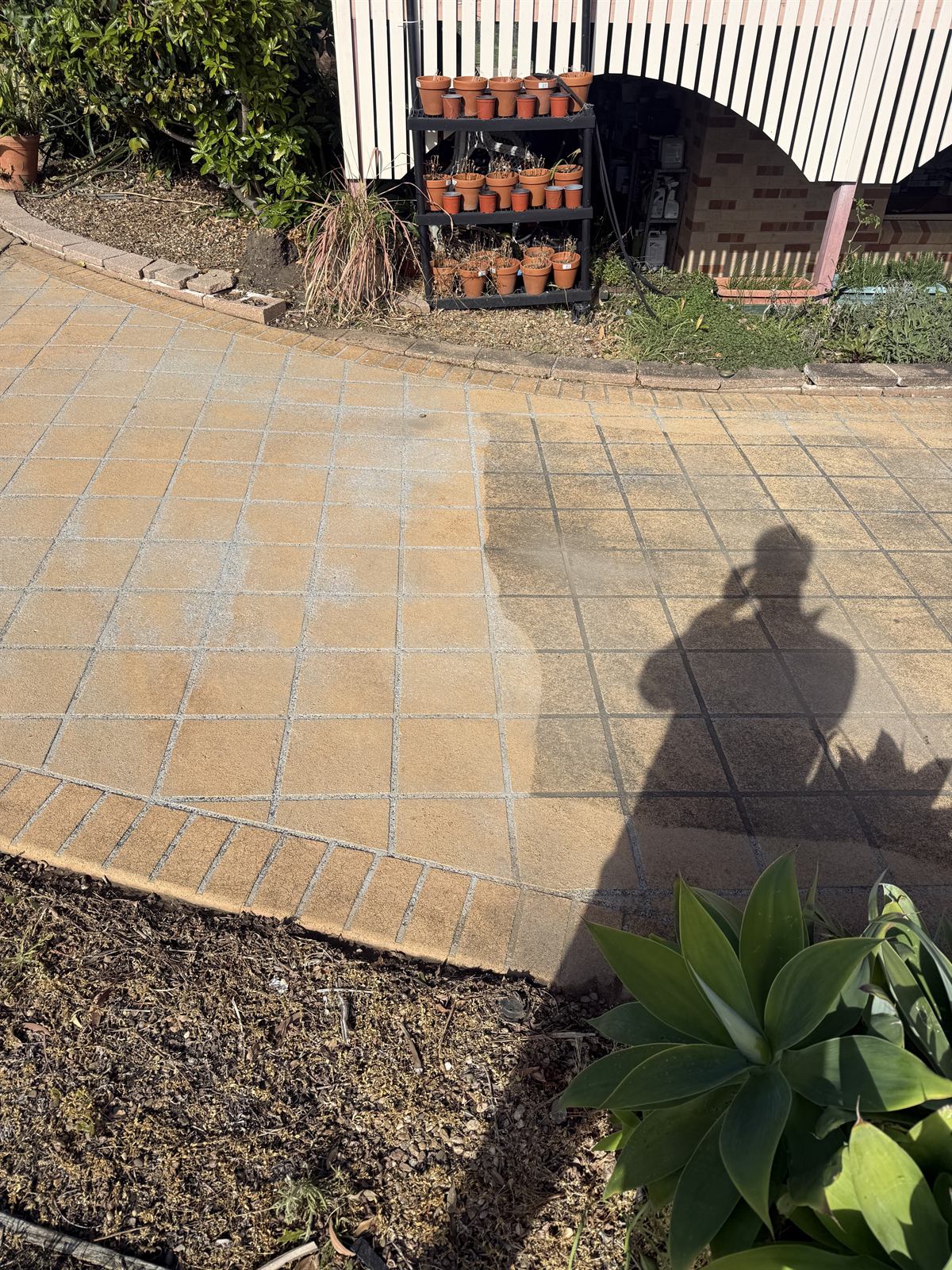 Paver pressure cleaning in progress, showing a visible clean section