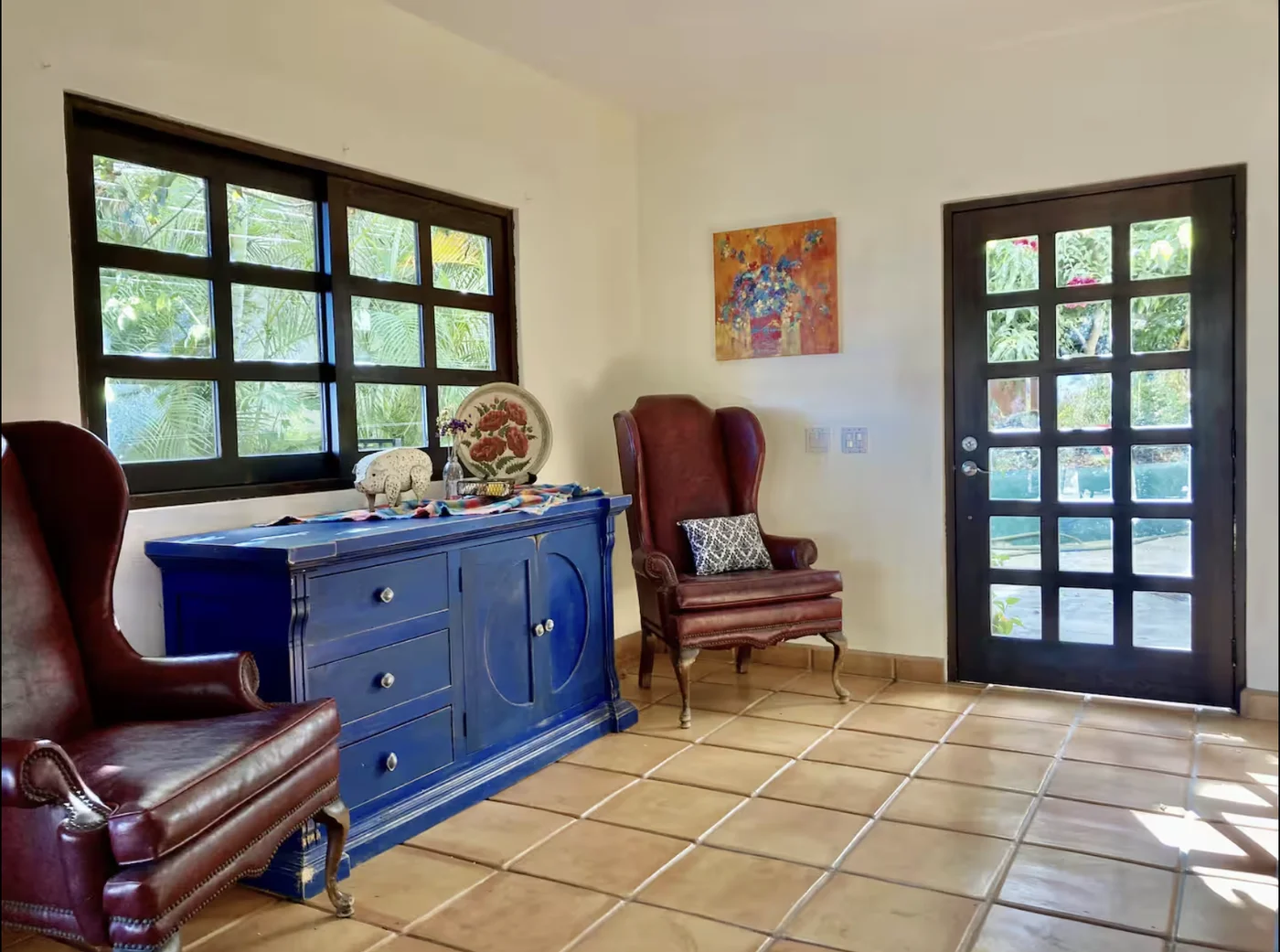 Entry sitting room at Casa Alba with a cobalt sideboard, leather wingbacks and French doors to the garden