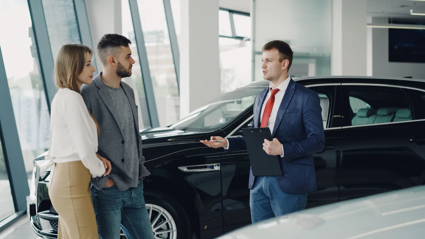 A couple exploring a vehicle with a dealership salesperson