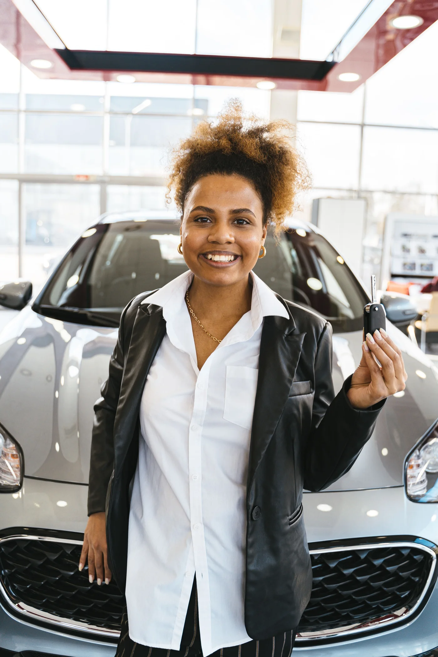 A customer holding vehicle keys in a dealership showroom