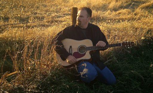 Ted Gaunt playing guitar in a golden Iowa field at sunset