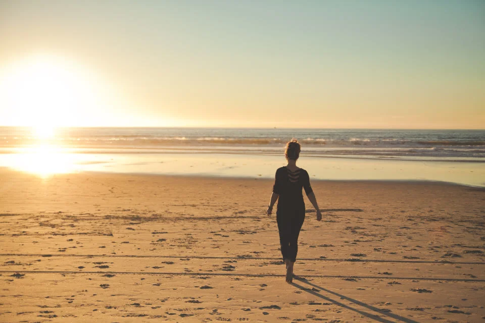Mujer caminando por la orilla al atardecer