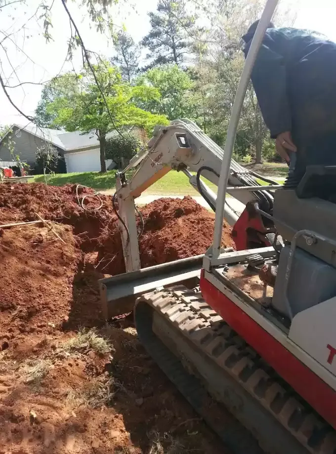 Mini excavator digging a sewer trench in a metro Atlanta yard