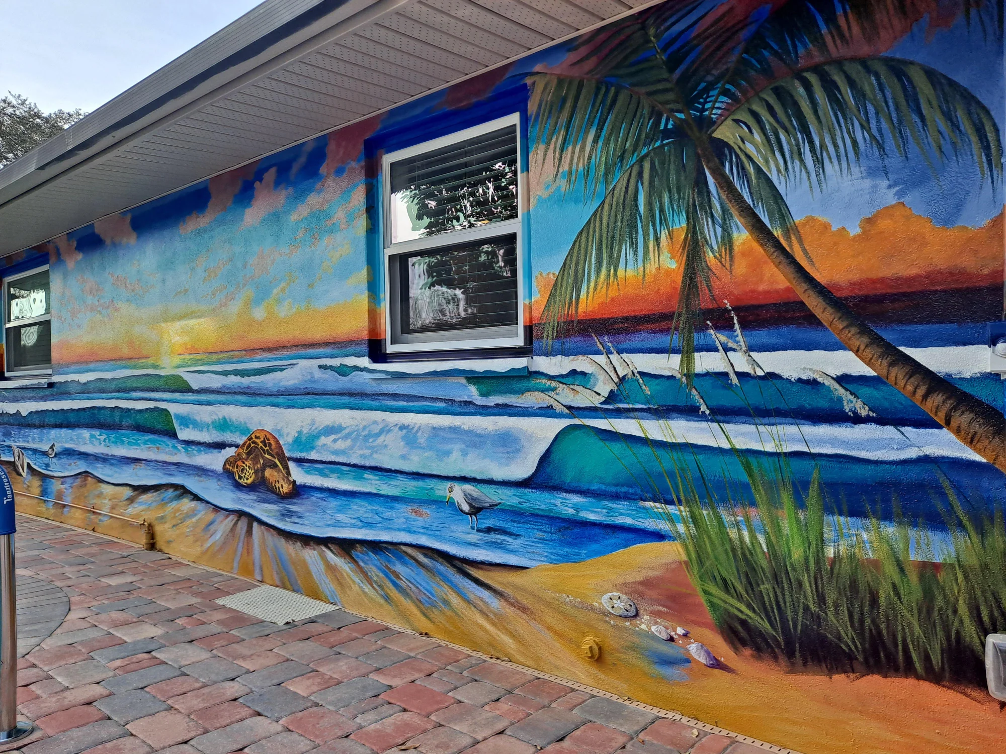 Coastal ocean and palm mural painted across an exterior wall