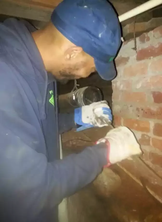 Plumber soldering copper pipe at an exterior brick wall