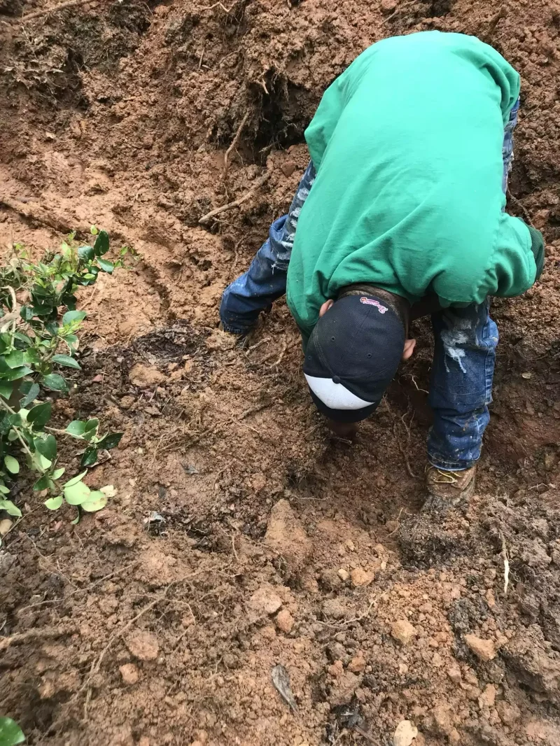 Crew member clearing soil around a cracked drain line
