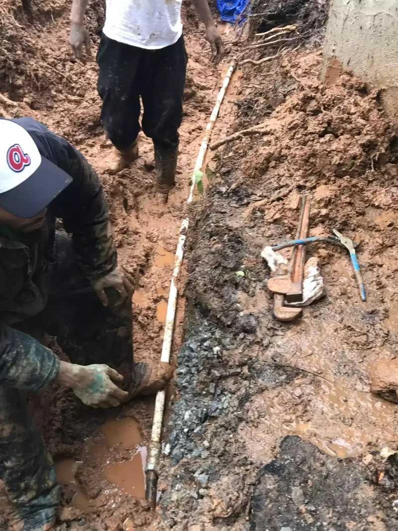 Plumber cutting into an old cast iron pipe in a trench