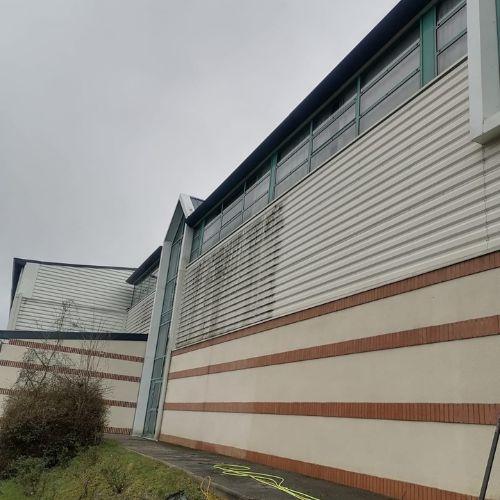 Bardage d'un gymnase communal marqué par des coulures vertes avant nettoyage