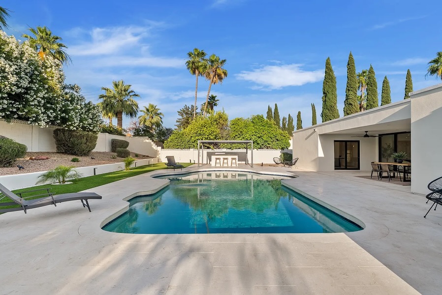 Resort-style backyard with pool, travertine deck, pergola and palms in Phoenix AZ