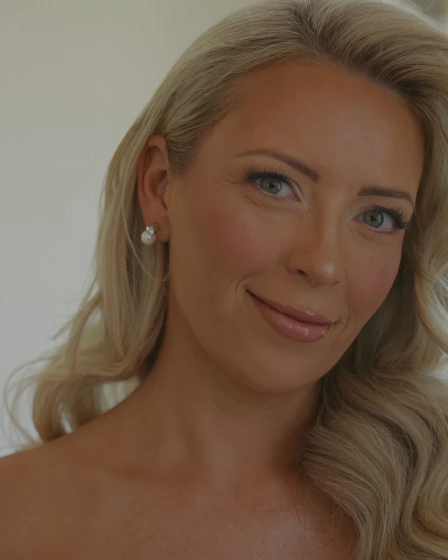 A bride smiling into the camera as she gets ready