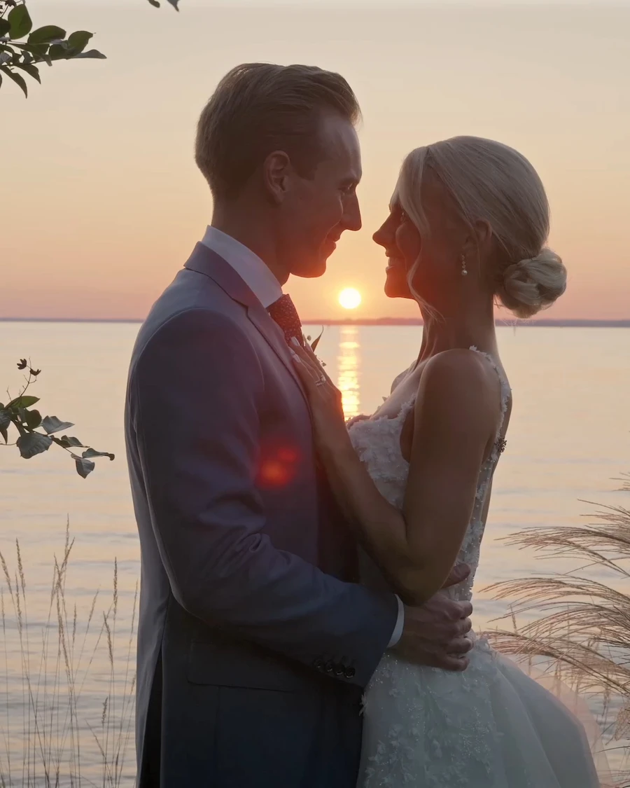 A couple holding each other by the water at sunset
