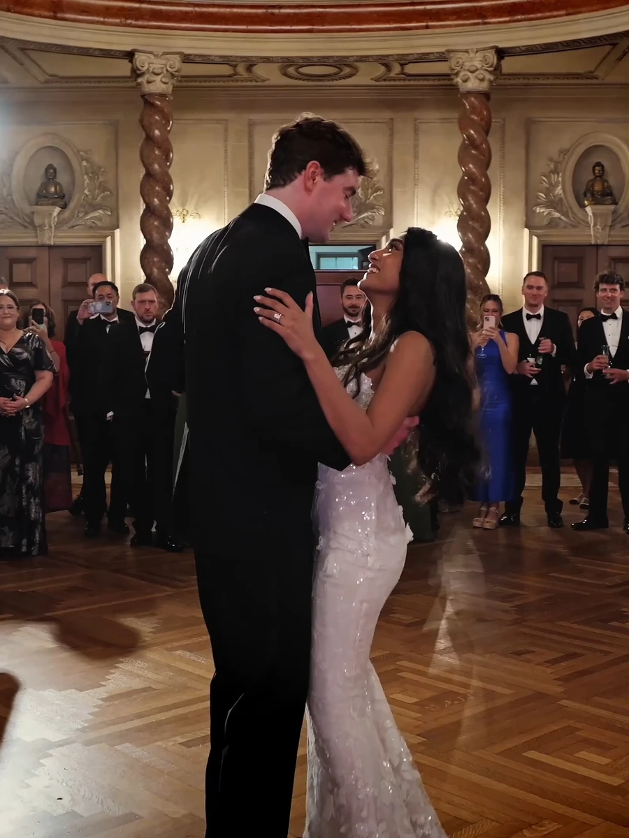 A couple's first dance in a grand ballroom, their guests all around them